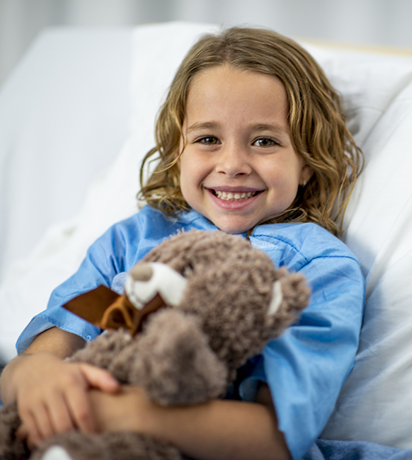 Girl In Hospital Bed with stuffed brown teddy bear