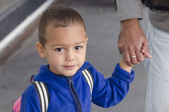 young boy in blue hoodie holding hand of older gentleman