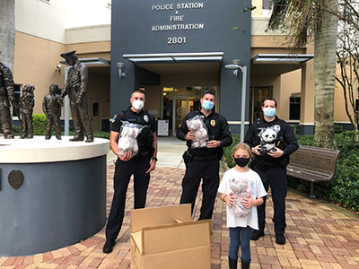 Coral Springs police officers and young girl with donated little hugs cute plushies in wrappers